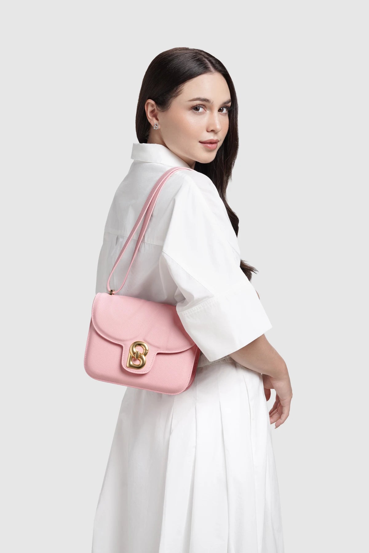 Model memakai Buttonscarves Alba Bag Medium warna pink tampak samping